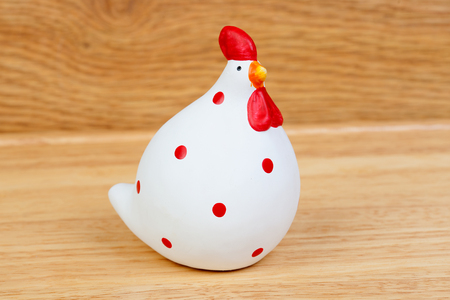 Funny hen ceramic white and red on a wooden backgroundの写真素材