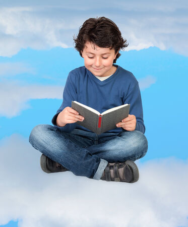 Adorable child reading sitting on the cloudsの写真素材