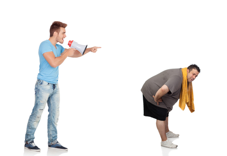 Fat men and his personal trainer with a megaphone isolated on a white backgroundの写真素材