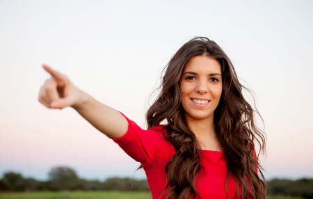 Beautiful young woman indicating something in the countryside with beautiful lightの写真素材