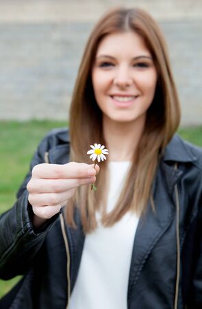 Pretty cool girl offering a beautiful flower. Focus in the daisyの写真素材