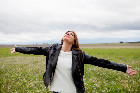 Beautiful woman with leather jacket relaxing in the countryside surrounded by flowers