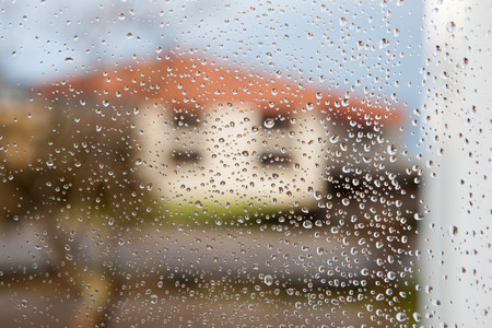 Wet glass with drops of rain fall on the street,