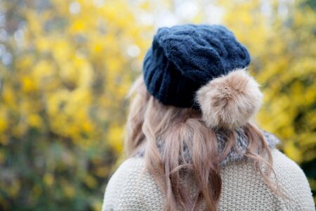 Woman back with wool hat and a flowered tree of backgroundの写真素材