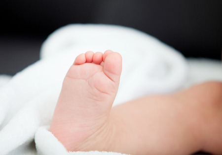 Little foot of a baby sitting on the sofa at homeの写真素材