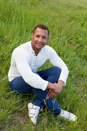Afroamerican guy on a park sitting on the grassの写真素材