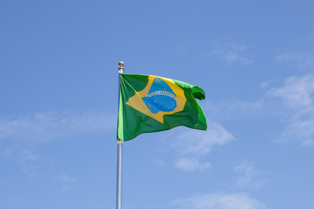 Brazilian flag waving in the mast with blue sky backgroundの写真素材