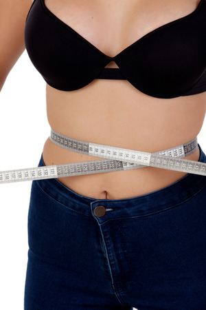 Thin woman with black bra measuring her waist with a tape measureの写真素材