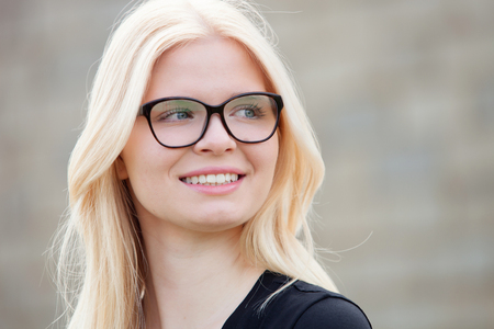 Young blonde girl with glasses outside smilingの写真素材