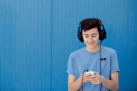 Teen listening to music with headphones on blue backgroundの写真素材