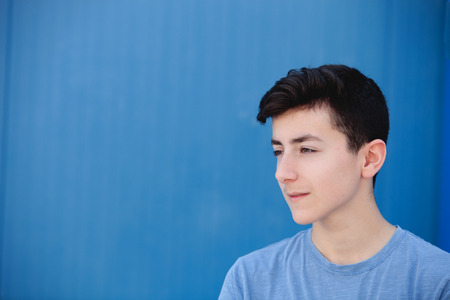 Portrait of a teenager rebellious man with a blue backgroundの写真素材
