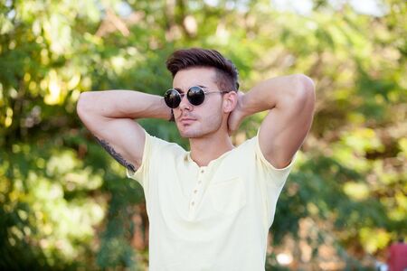 Attractive guy in the park with sunglasses and yellow t-shirtの写真素材