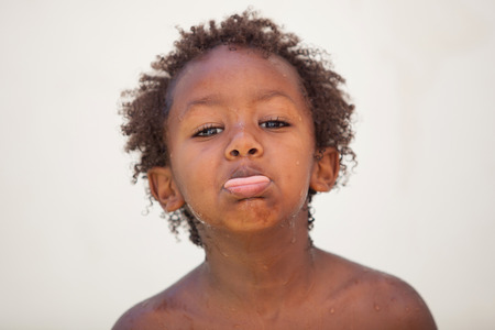 Funny african kid sticking his tongue out looking at cameraの写真素材