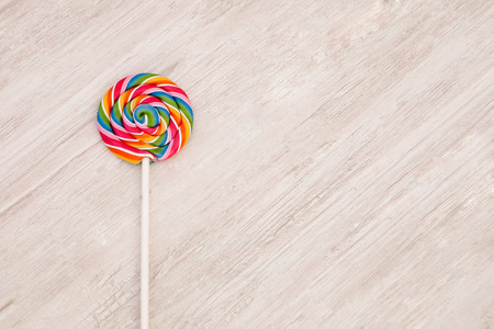 Nice round lollipop with many colors in a spiral on a wooden backgroundの写真素材