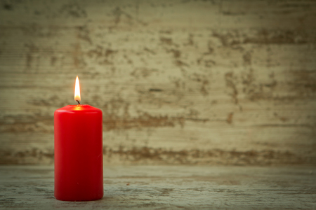 Red Christmas candle on a white wooden backgroundの写真素材