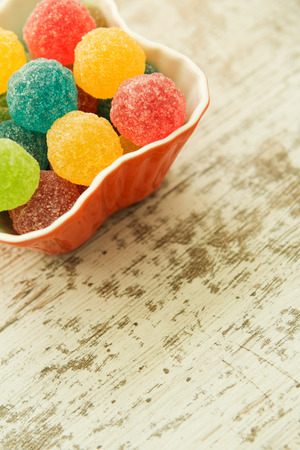 Bowl filled with jelly beans colors on a wooden tableの写真素材