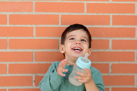 Smiling little child taking a bottle on the streetの写真素材