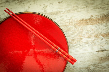 Oriental ceramic plate and chopsticks in red on a wooden backgroundの写真素材