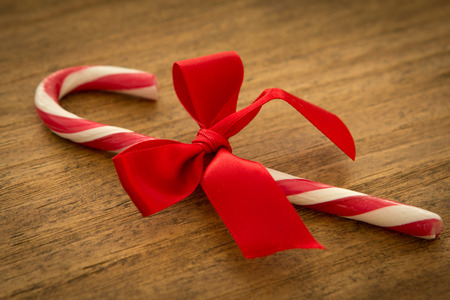 Red candy cane with a beautiful bow on a wooden backgroundの写真素材