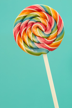 Nice lollipop with many colors in a spiral on a blue backgroundの写真素材
