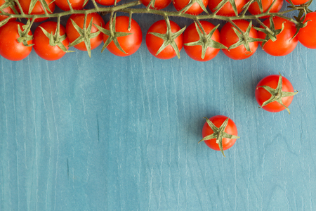 Small cherry tomatoes with leaf on a blue wooden surfaceの写真素材
