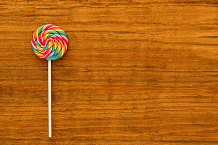 Nice lollipop with many colors in a spiral on a wooden backgroundの写真素材