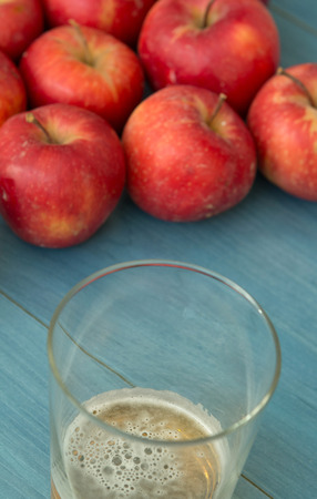Ripe red apples with a glass of cider blue table close upの写真素材