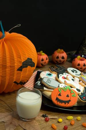 Creepy Halloween cookies next to a milk glass on a wooden tableの写真素材