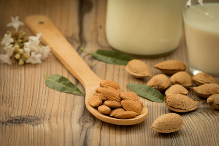 Almond milk with almonds on a wooden table and focus with shallow depth of fieldの写真素材