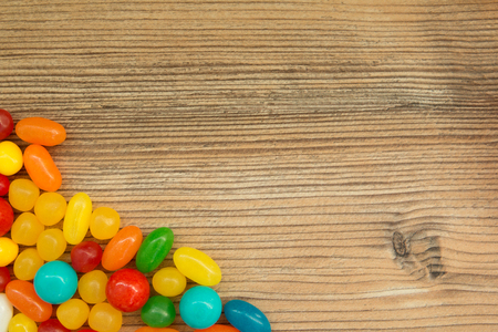Colorful jelly beans shaped a frame to write your text on a wooden backgroundの写真素材