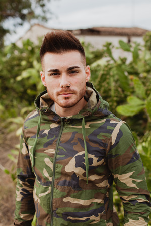 Attractive guy with military jacket and plants backgroundの写真素材