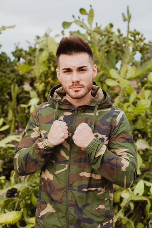 Attractive guy with military jacket and plants backgroundの写真素材