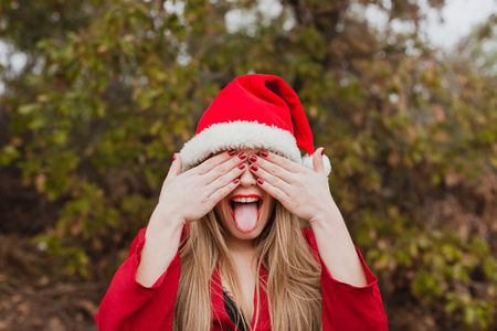 Young woman with Christmas hat and red lips in the forestの写真素材
