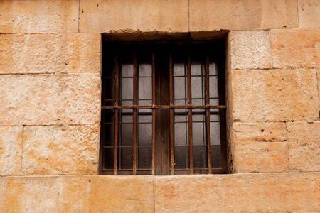 Window with rusty grilles on a brown stone facade