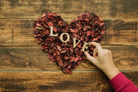 Beautiful heart maked with dry petals on a wooden rustic tableの写真素材