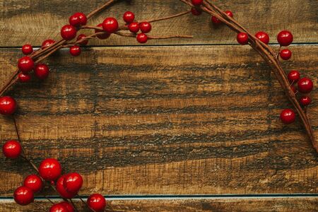 Christmas branch with red berries on a rustic wooden background