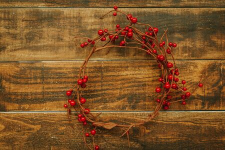 Christmas branch with red berries on a rustic wooden backgroundの写真素材