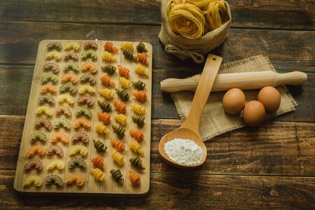 Colorful pasta with nice shapes lined up on wooden boardの写真素材
