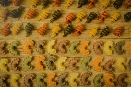 Colorful pasta with nice shapes lined up on wooden boardの写真素材