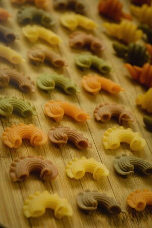 Colorful pasta with nice shapes lined up on wooden boardの写真素材