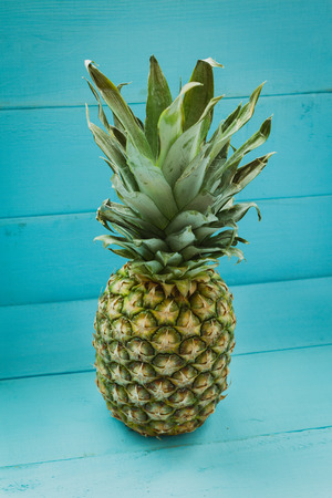 Green pineapple on a blue wooden tableの写真素材