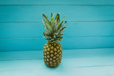 Green pineapple on a blue wooden tableの写真素材