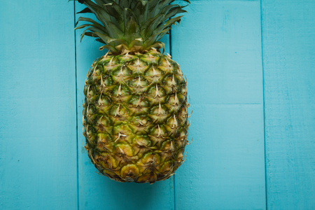 Green pineapple on a blue wooden tableの写真素材