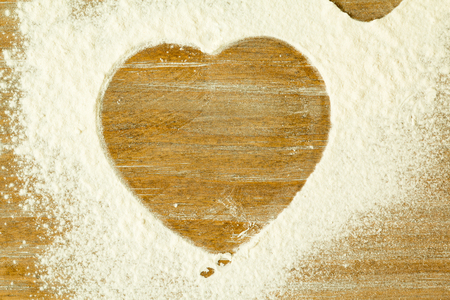 Heart shape in the sifted flour on the tableの写真素材