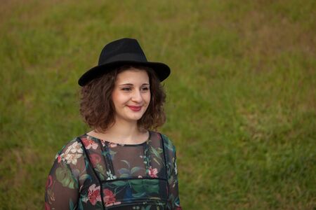 Beautiful girl with flowered dress an black hat in the landscapeの写真素材