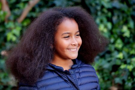 Pretty girl with long afro hair in the garden with a blue coatの写真素材