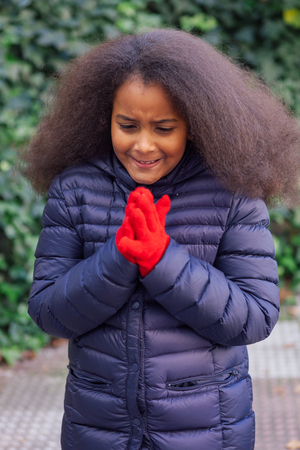 Pretty girl with long afro hair in the garden with a blue coatの写真素材