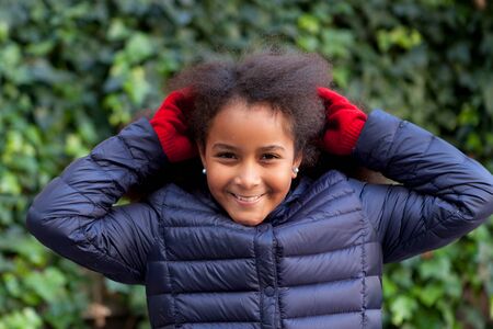 Pretty girl with long afro hair in the garden with a blue coatの写真素材
