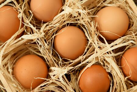 Eggs on straw placed on a wooden tableの写真素材