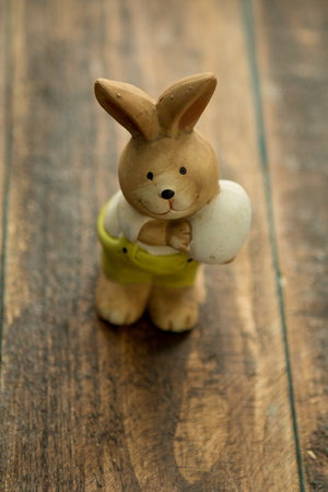 Ceramic painted rabbits for Easter decoration on a wooden backgroundの写真素材